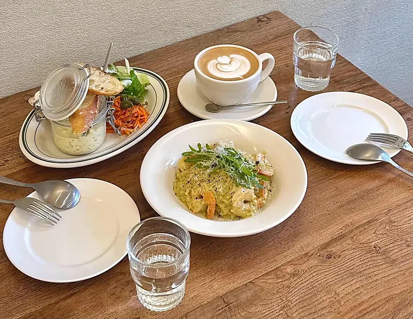 A cafe brunch table with a latte, risotto and fresh bread